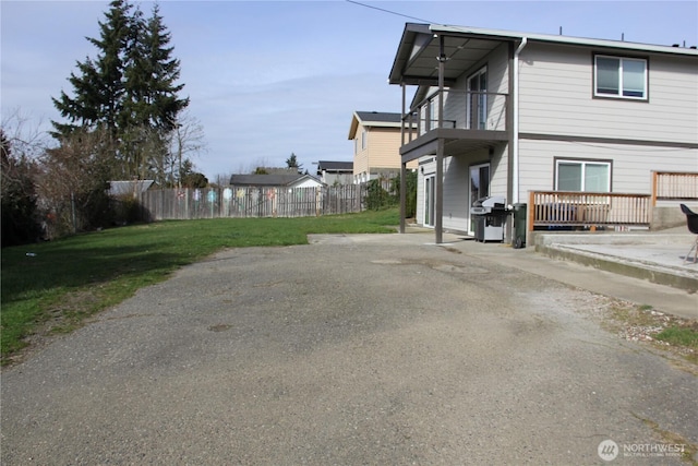 view of home's exterior featuring a lawn, fence, and a balcony