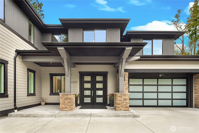 property entrance featuring stone siding, concrete driveway, and an attached garage