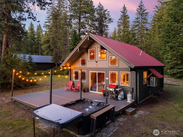 rear view of house with faux log siding, metal roof, and a wooden deck