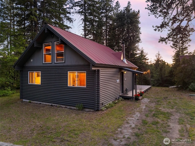 property exterior at dusk with metal roof and log veneer siding