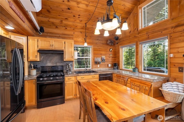 kitchen with lofted ceiling, wood walls, a sink, black appliances, and plenty of natural light