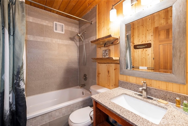 bathroom featuring wooden walls, visible vents, tiled shower / bath, and toilet