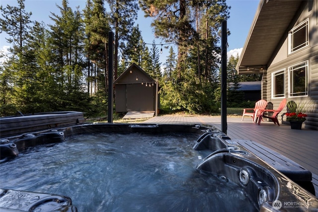 wooden deck featuring a storage shed, a hot tub, and an outdoor structure