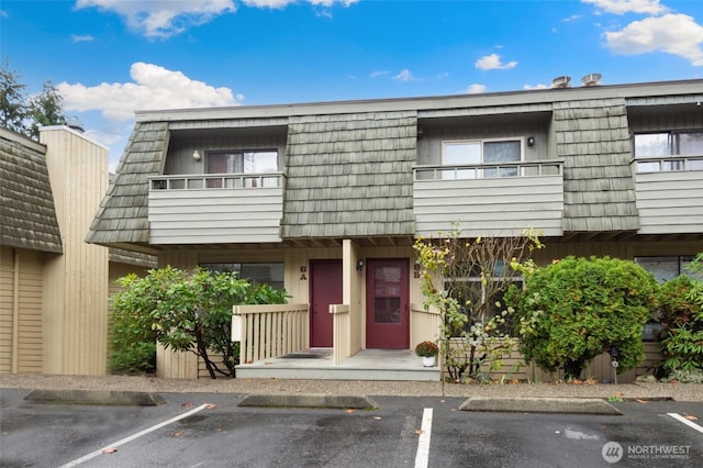 multi unit property featuring uncovered parking, mansard roof, and a balcony