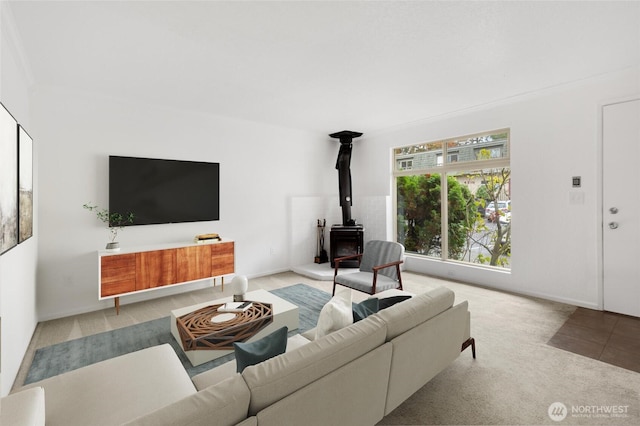 carpeted living area with a wood stove and baseboards