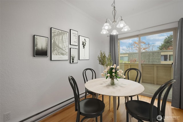 dining space featuring crown molding, a chandelier, baseboard heating, and wood finished floors