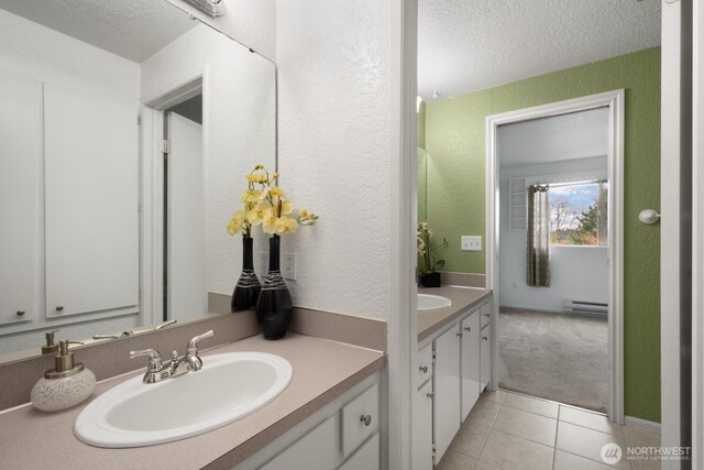 bathroom featuring a textured wall, a baseboard heating unit, vanity, a textured ceiling, and tile patterned floors