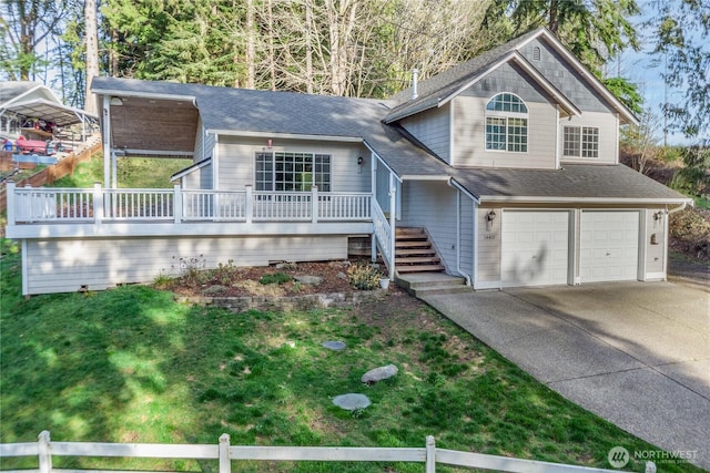 split level home featuring a garage, fence, stairs, concrete driveway, and a front yard