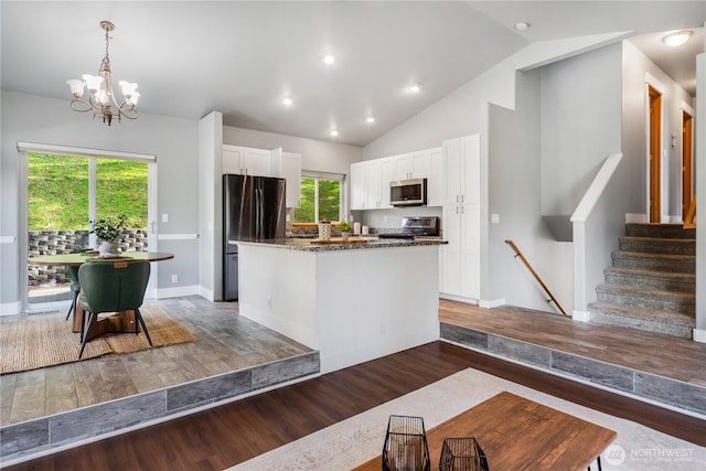 kitchen featuring white cabinets, dark stone counters, a kitchen island, wood finished floors, and stainless steel appliances