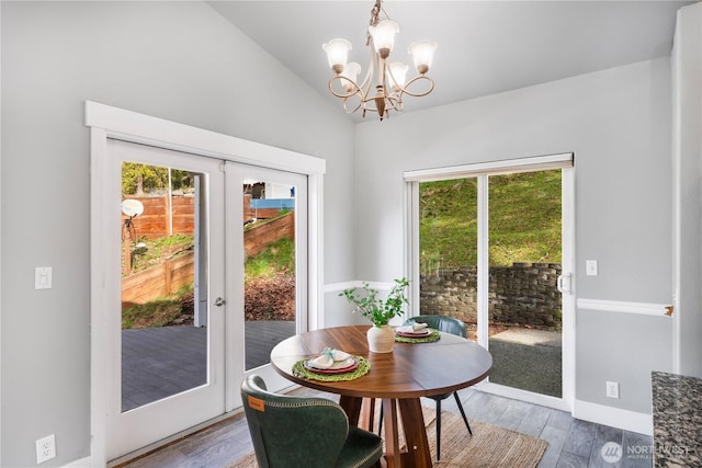 dining space featuring a chandelier, lofted ceiling, french doors, and wood finished floors