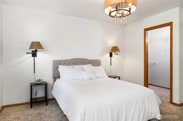 carpeted bedroom with an inviting chandelier, a spacious closet, baseboards, and a closet