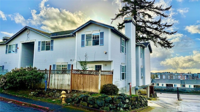 view of side of property featuring a chimney and fence