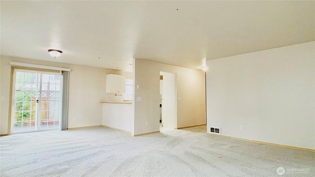 spare room with light carpet, visible vents, and baseboards