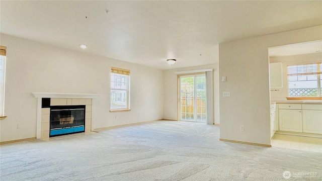 unfurnished living room featuring light carpet, a fireplace, and baseboards