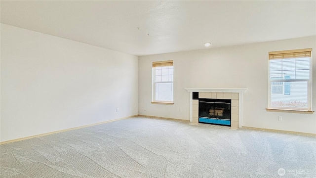 unfurnished living room featuring light carpet, baseboards, and a tiled fireplace