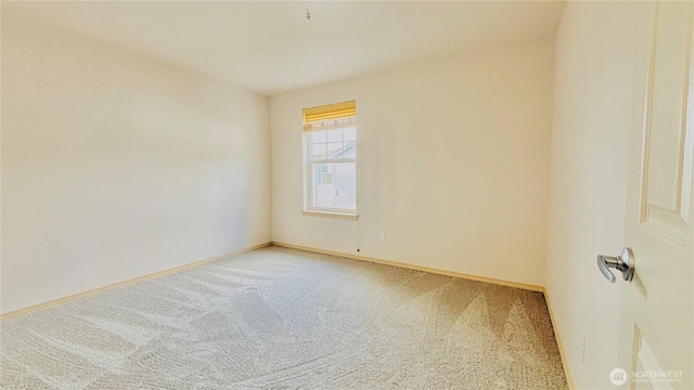 carpeted empty room featuring baseboards