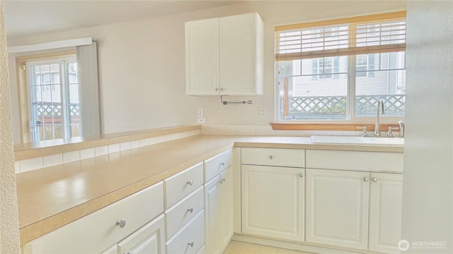 kitchen featuring a sink, white cabinetry, and a healthy amount of sunlight