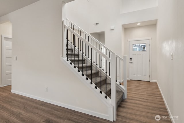 entrance foyer with a high ceiling, dark wood-style flooring, and baseboards