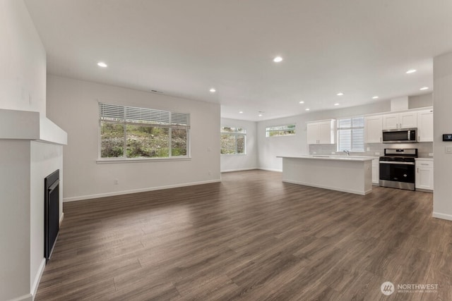 unfurnished living room featuring recessed lighting, dark wood-style flooring, a fireplace, and baseboards