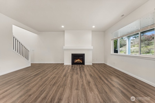 unfurnished living room featuring wood finished floors, recessed lighting, a glass covered fireplace, and baseboards