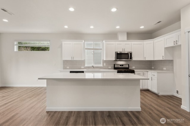 kitchen featuring visible vents, a kitchen island, appliances with stainless steel finishes, light countertops, and a sink