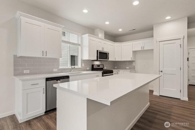 kitchen with white cabinetry, appliances with stainless steel finishes, dark wood-style flooring, and a sink