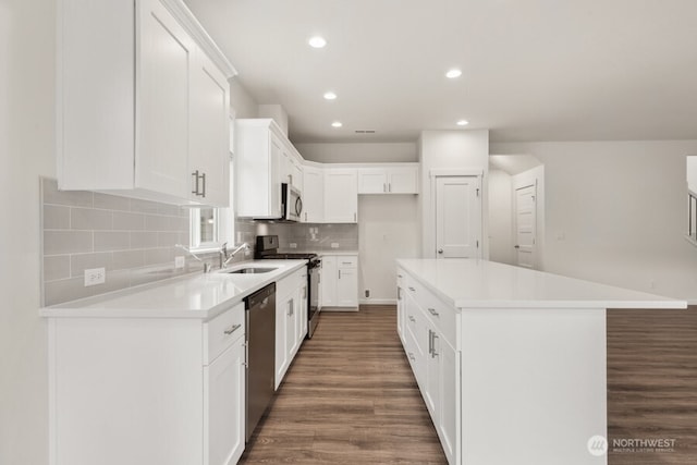 kitchen with dark wood finished floors, decorative backsplash, a center island, stainless steel appliances, and a sink