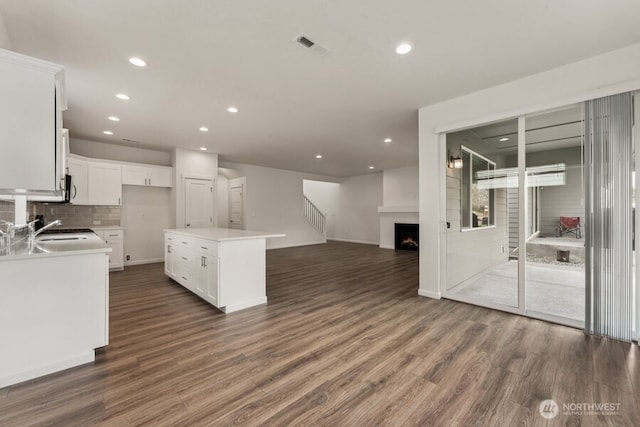 kitchen with a fireplace, dark wood-style flooring, a sink, and open floor plan