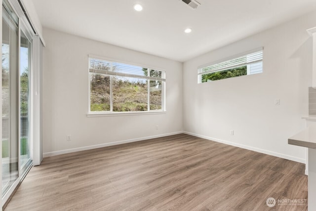 spare room with baseboards, recessed lighting, wood finished floors, and a healthy amount of sunlight