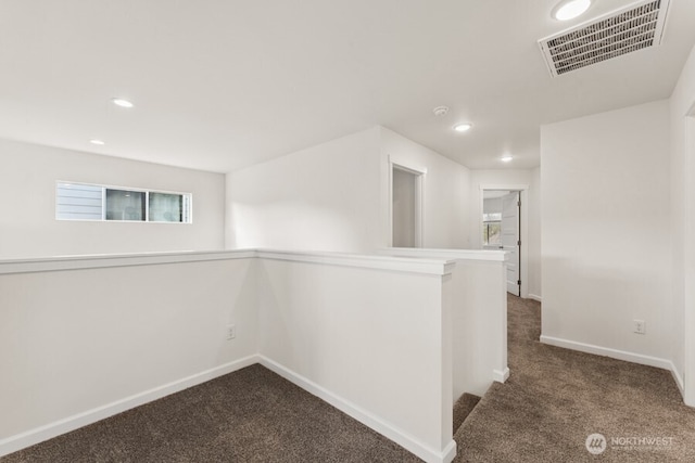 interior space with baseboards, visible vents, an upstairs landing, dark carpet, and recessed lighting