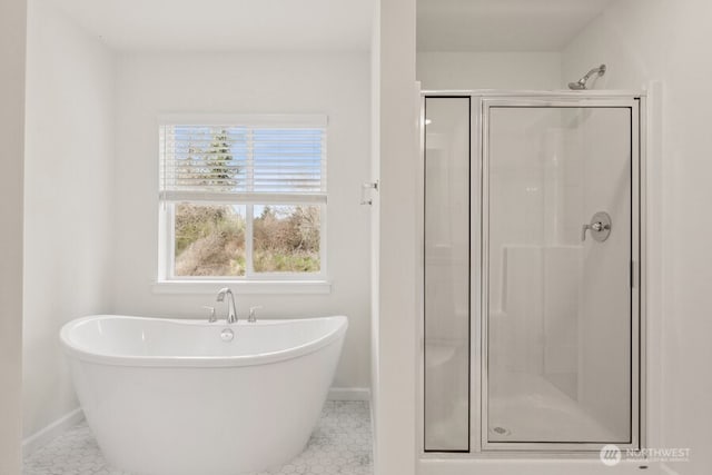 full bath with tile patterned flooring, a freestanding bath, a shower stall, and baseboards