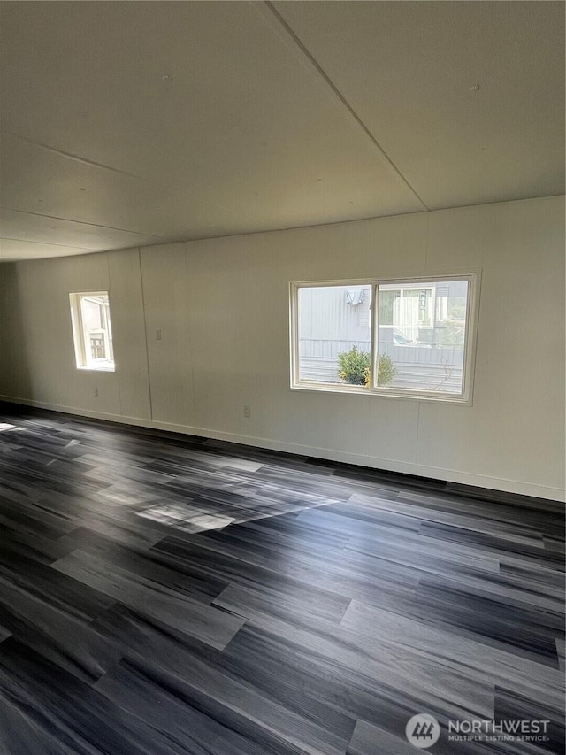 unfurnished room with a healthy amount of sunlight and dark wood-style floors