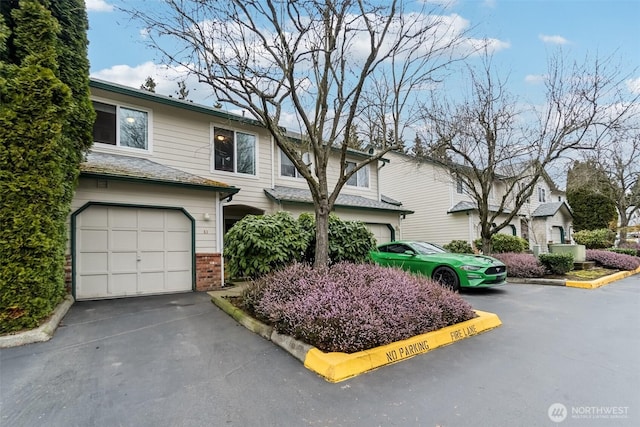 view of property featuring an attached garage, brick siding, and driveway