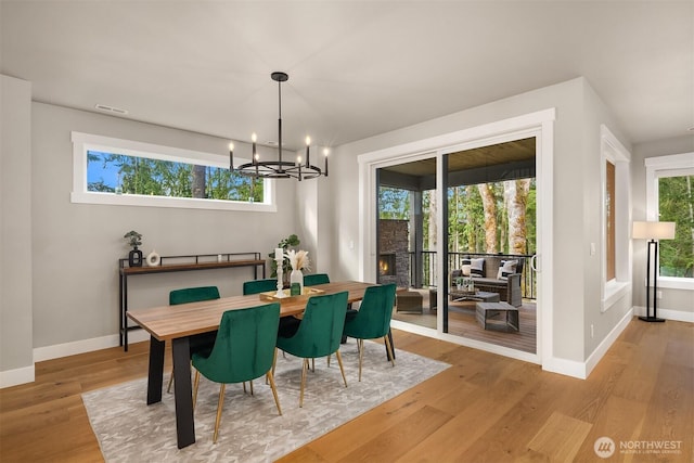 dining area featuring light wood finished floors, visible vents, baseboards, and a notable chandelier