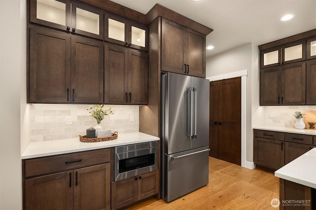 kitchen with light countertops, appliances with stainless steel finishes, light wood-type flooring, and dark brown cabinetry