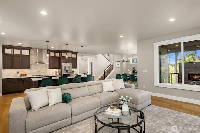 living area with a chandelier, light wood finished floors, stairway, and recessed lighting