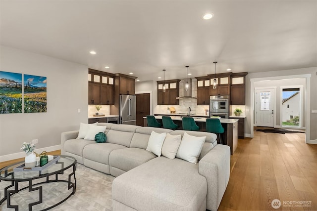 living area featuring light wood-type flooring, baseboards, and recessed lighting