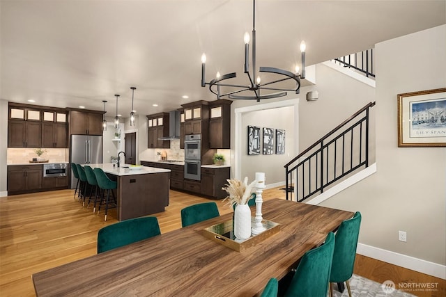 dining space featuring light wood finished floors, baseboards, stairway, a chandelier, and recessed lighting