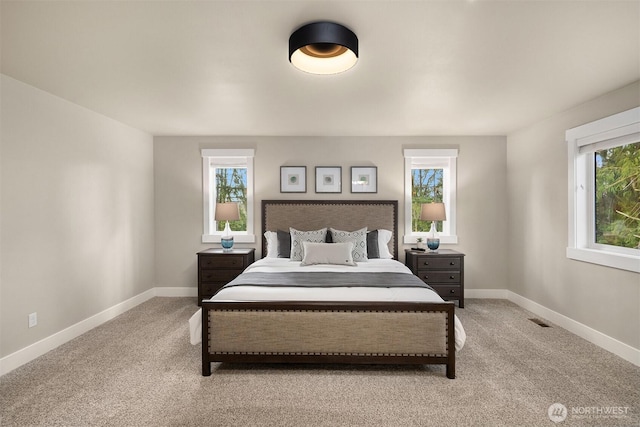 bedroom with multiple windows and light colored carpet