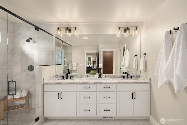 full bathroom with marble finish floor, double vanity, a sink, and a marble finish shower