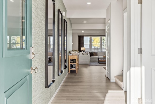 hall featuring light wood-style floors, baseboards, and recessed lighting