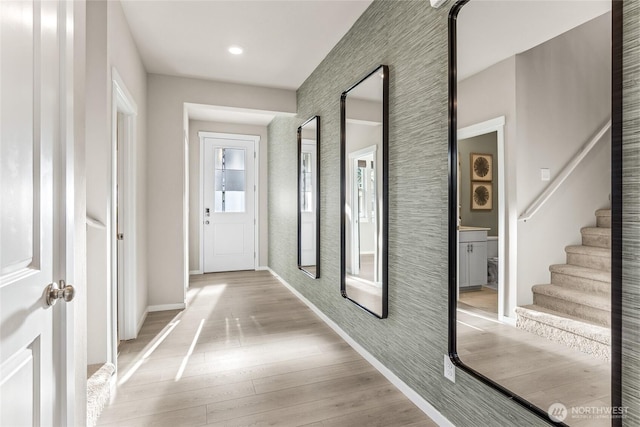 hallway featuring light wood-style floors, stairs, and baseboards