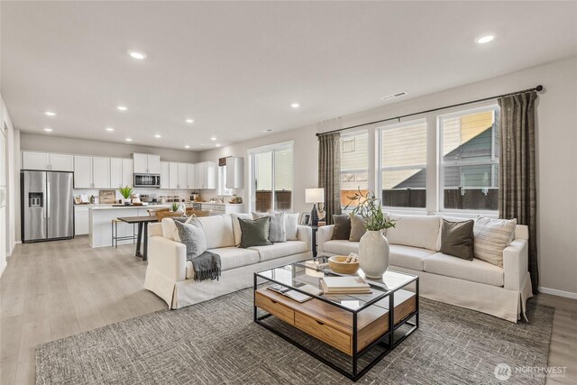 living room with light wood-style floors, recessed lighting, visible vents, and baseboards