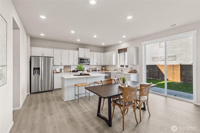 dining space featuring light wood-type flooring, visible vents, baseboards, and recessed lighting