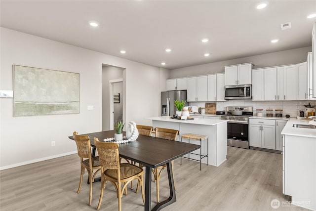 dining space with light wood finished floors, visible vents, and recessed lighting