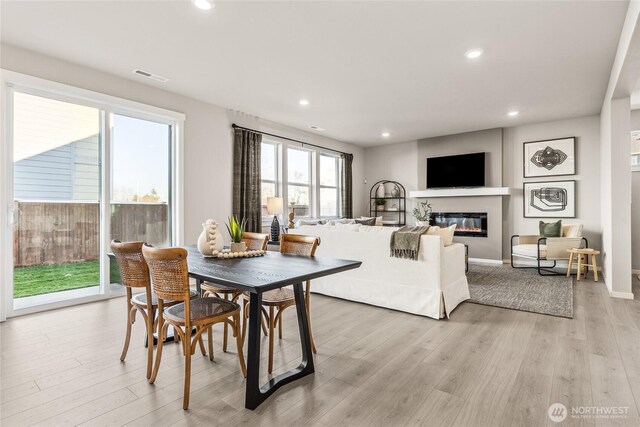 dining room featuring visible vents, a glass covered fireplace, light wood-style flooring, and recessed lighting