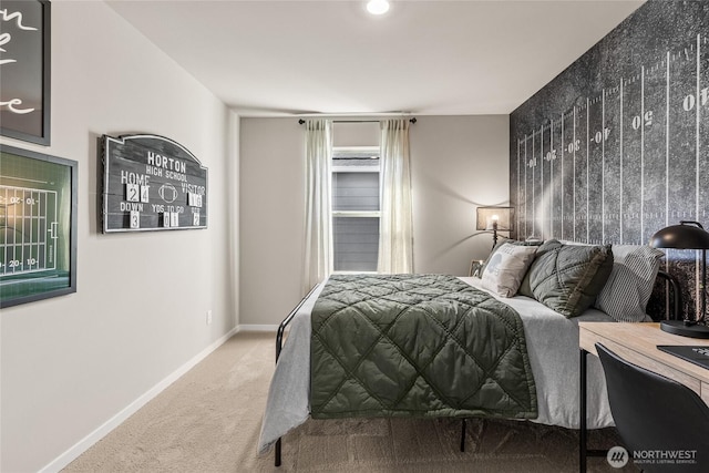 carpeted bedroom featuring an accent wall and baseboards