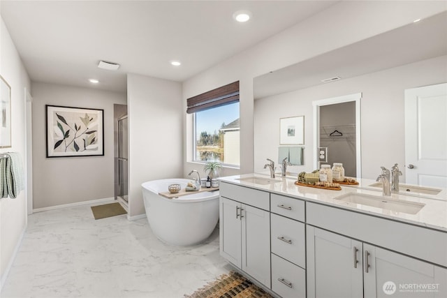 full bathroom featuring marble finish floor, a stall shower, a sink, and recessed lighting