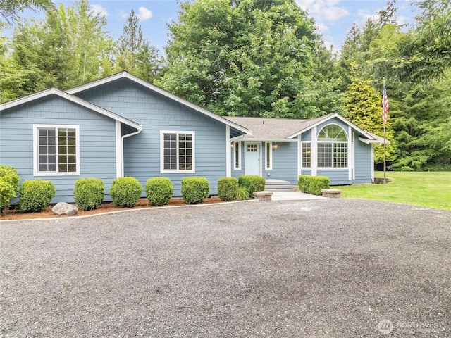 single story home with gravel driveway and a front lawn