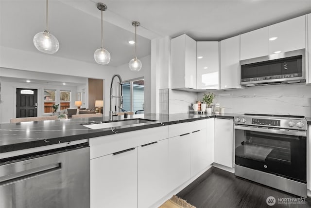 kitchen with appliances with stainless steel finishes, modern cabinets, a sink, and white cabinetry